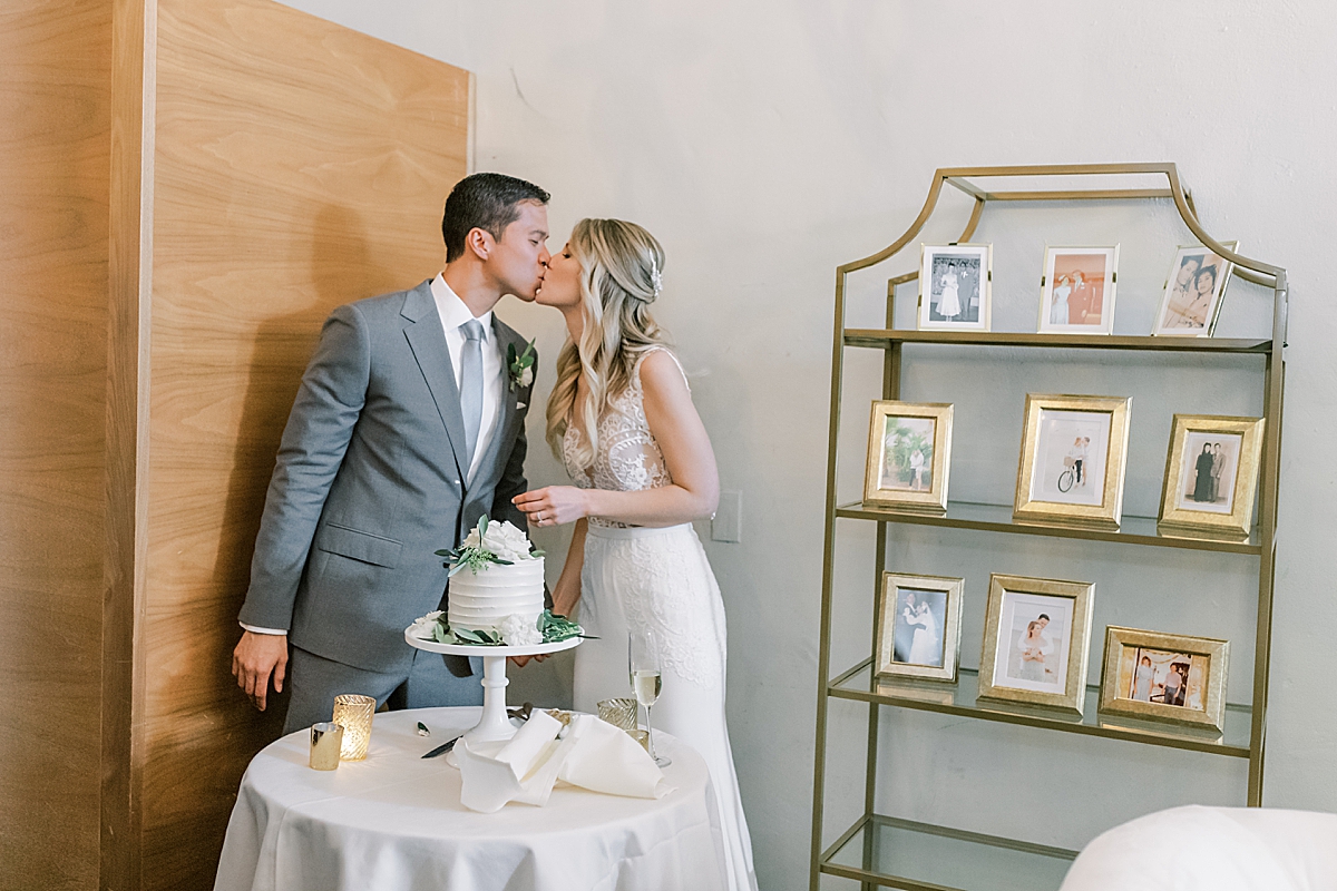 The couple kissing behind their cake during their Dancing at the couple's Villa & Vine Wedding