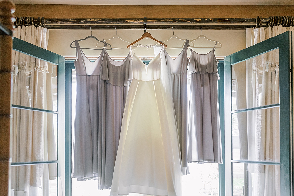 The bride's dress hanging in front of her bridesmaids dresses.