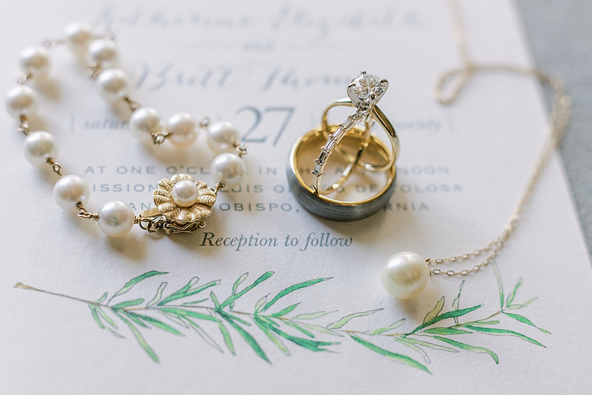 The bride's jewelry displayed on their wedding invitation at their San Luis Obispo Mission wedding venue.