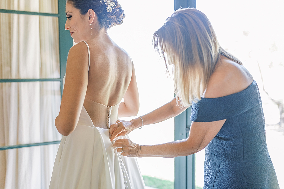 Kat's mom zipping up the back to her wedding dress.