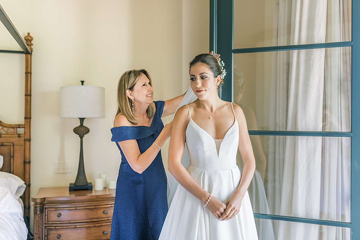 The mother of the bride smiling as she adjust the veil in her daughter's hair on their San Luis Obispo Mission wedding day.