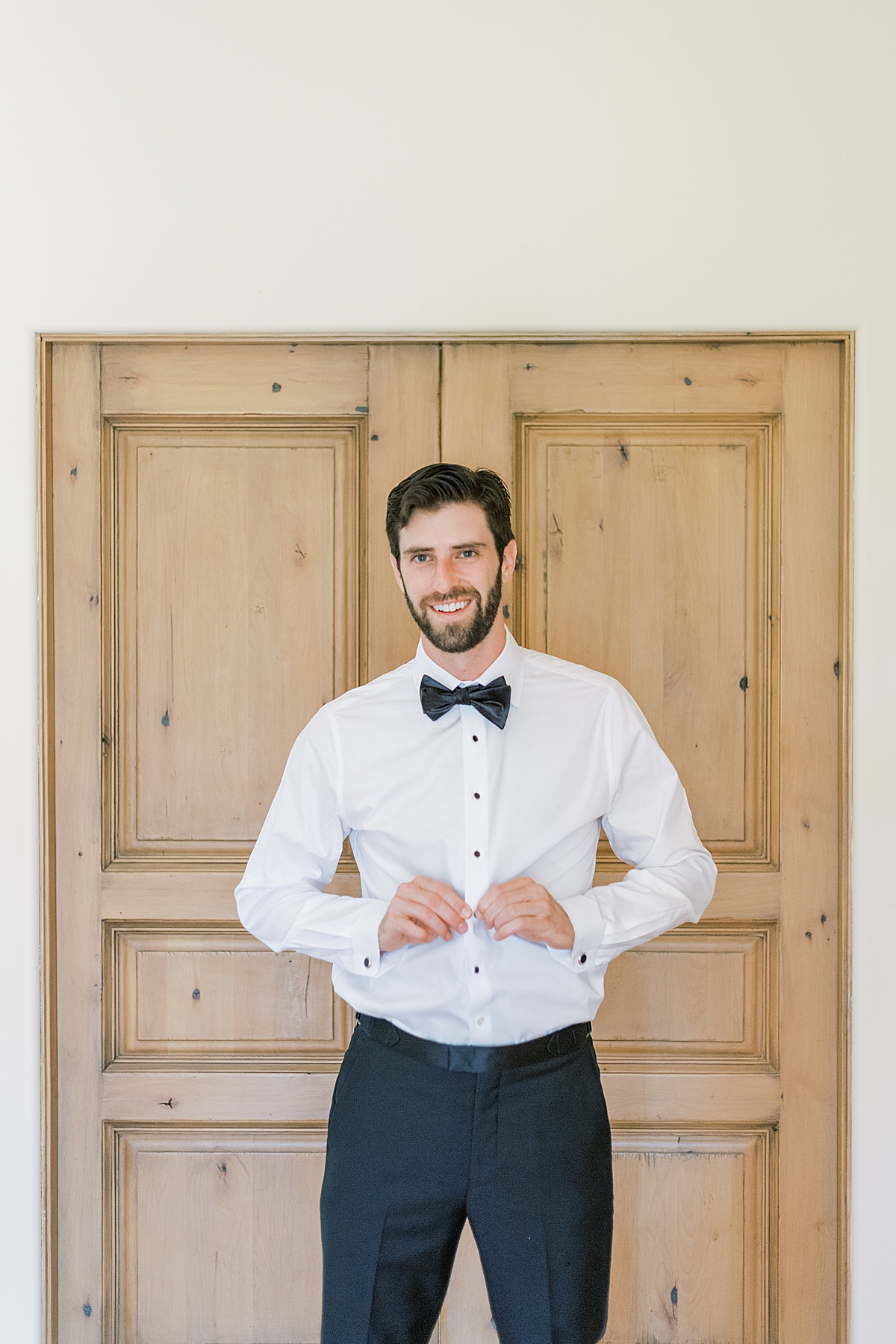 The groom buttoning his shirt before putting on his jacket.