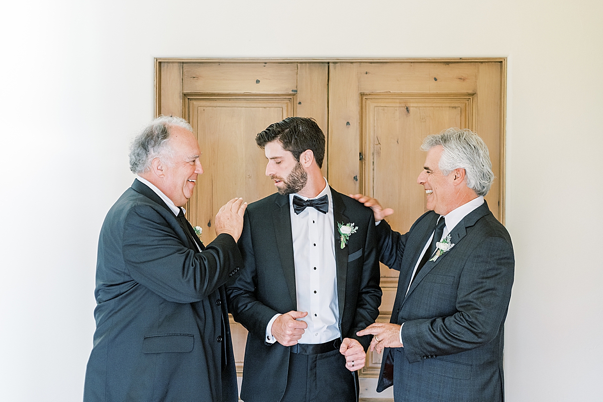 The father of the bride and the father of the groom helping the groom get ready.