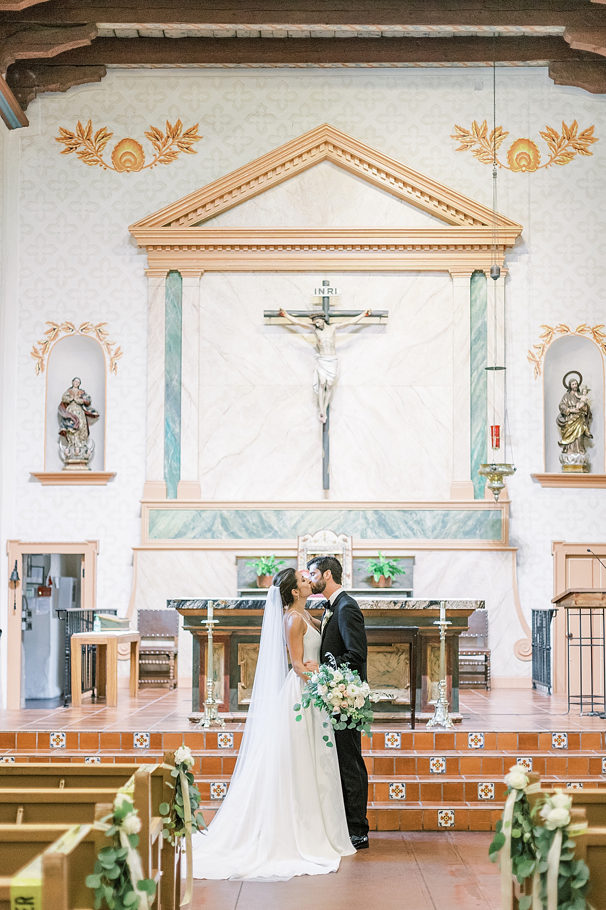 The newlyweds sharing a kiss in front of the altar at the Mission in San Luis Obispo, California. 