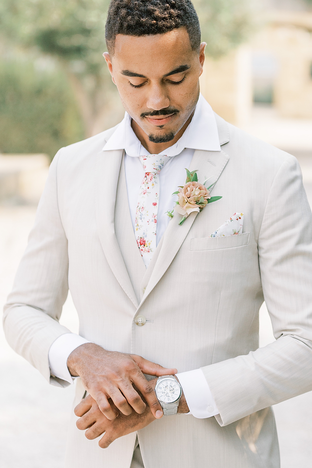 The groom smiling down at his watch at this Sunstone Villa Wedding editorial.