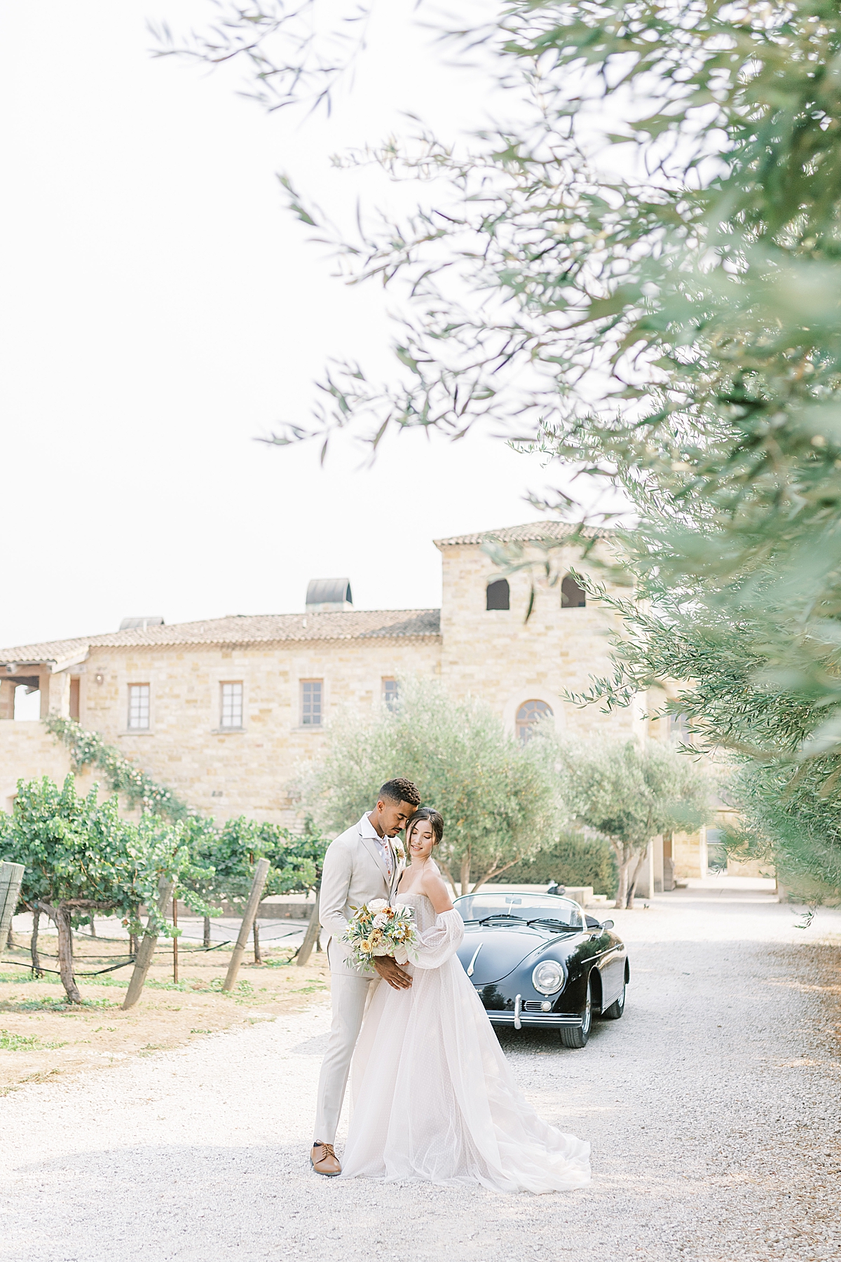 Luke leaning into his bride as she looks away from him near rows of vineyards and olive trees at this Sunstone Villa Wedding editorial.