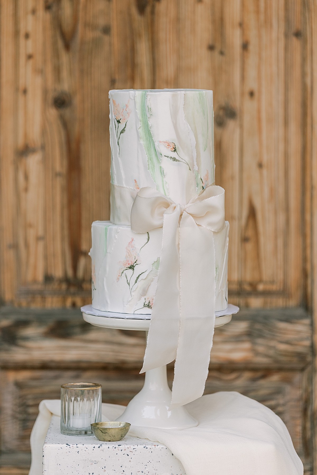 An image of the cake in front of a large wooden door at the Sunstone Villa Wedding editorial. 