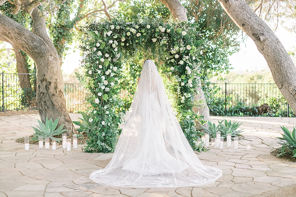 A bride in front of a floral arch that was used as the backdrop to her ceremony altar at one of the Santa Barbara Micro-Wedding Venues.