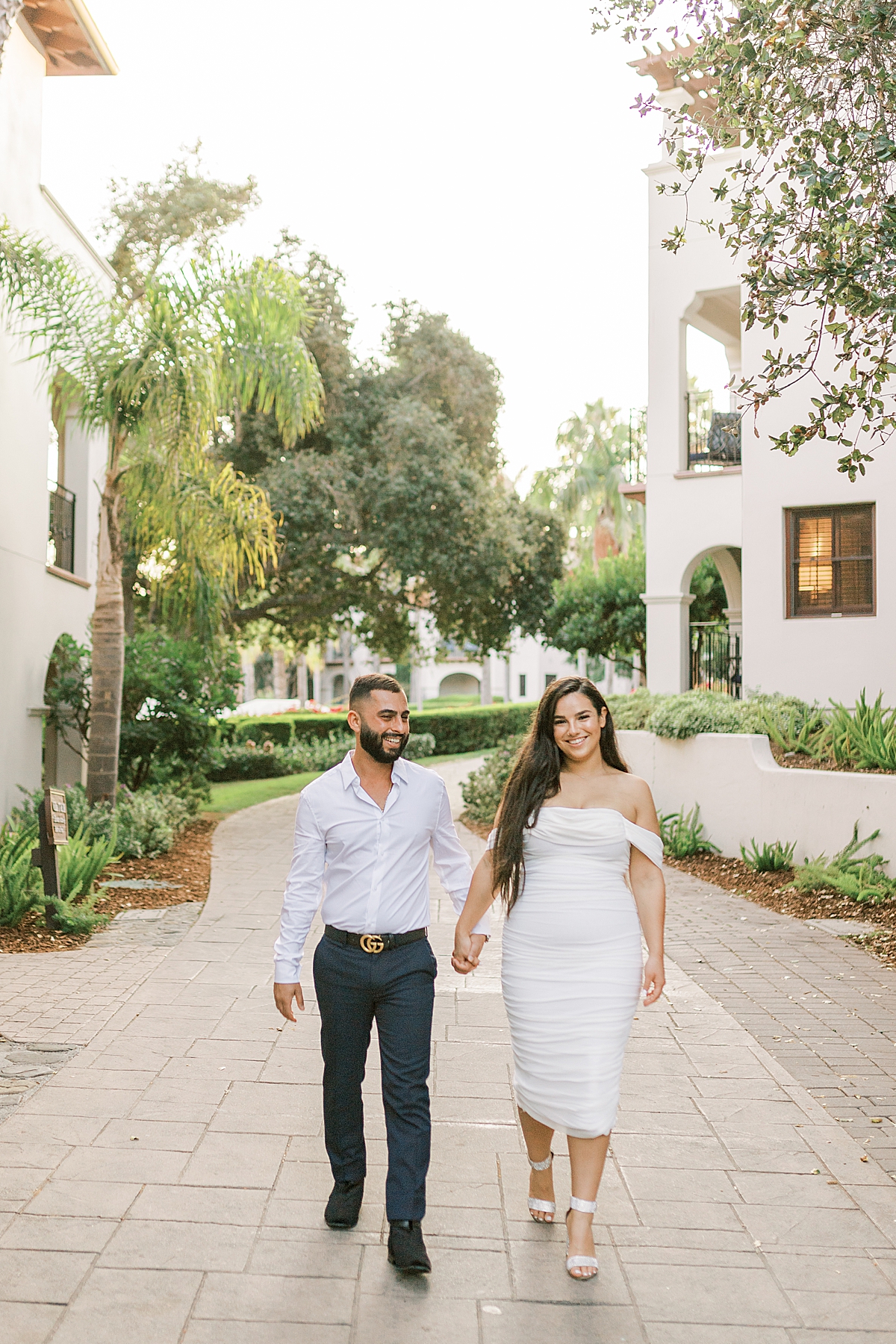Bella & Omid holding hands as they walk down a pathway at the Ritz-Carlton Bacara during their Santa Barbara Elopement