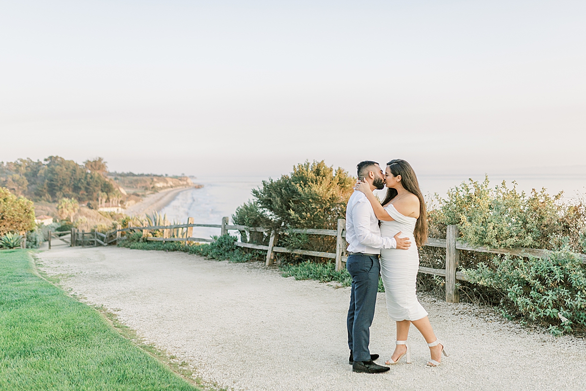 The couple sharing a kiss on a path above the ocean and beach below during their Santa Barbara Elopement