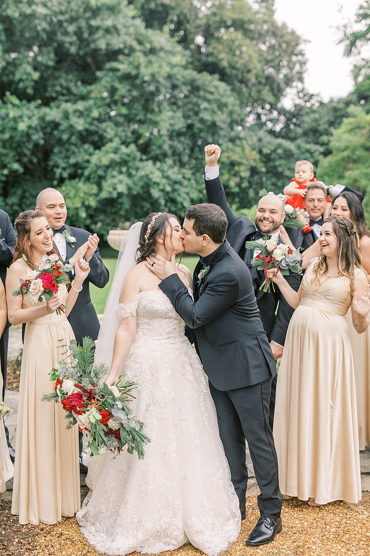 Sofia & Joey sharing a kiss as their wedding party cheers behind them.