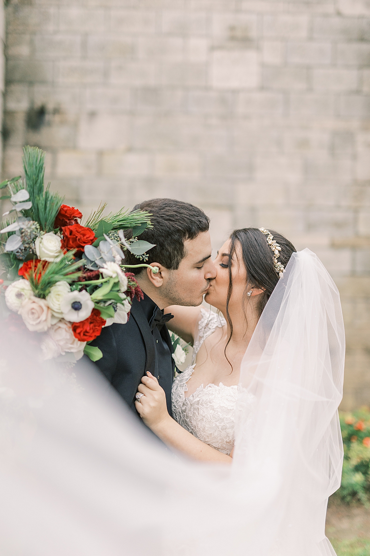 The couple sharing a kiss as her veil blows in the wind at their Ancient Spanish Monastery Wedding 