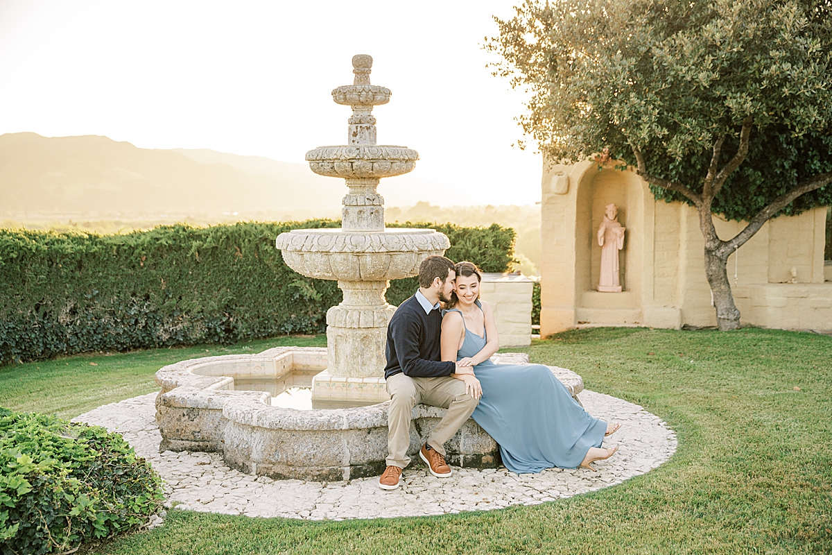 A couple sitting together on a water fountain at Whispering Rose Ranch.