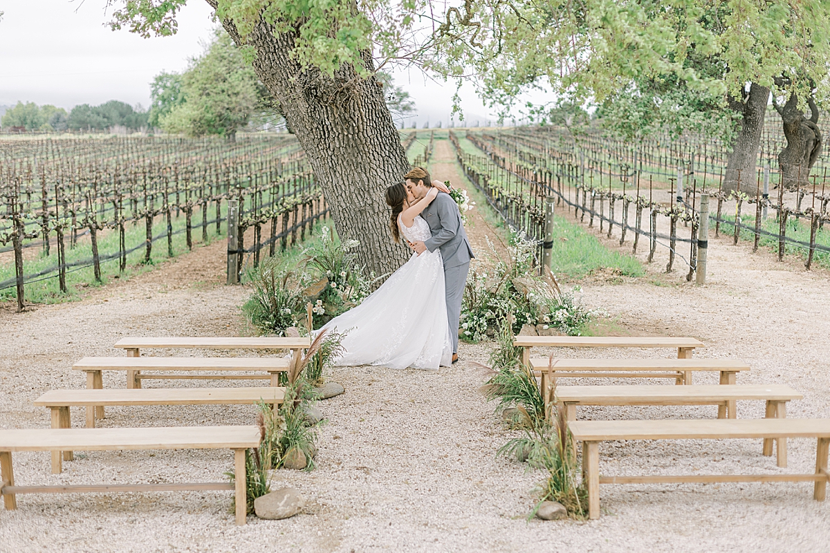 The couple sharing a kiss at the altar under a large oak tree as he dips her backwards slightly.