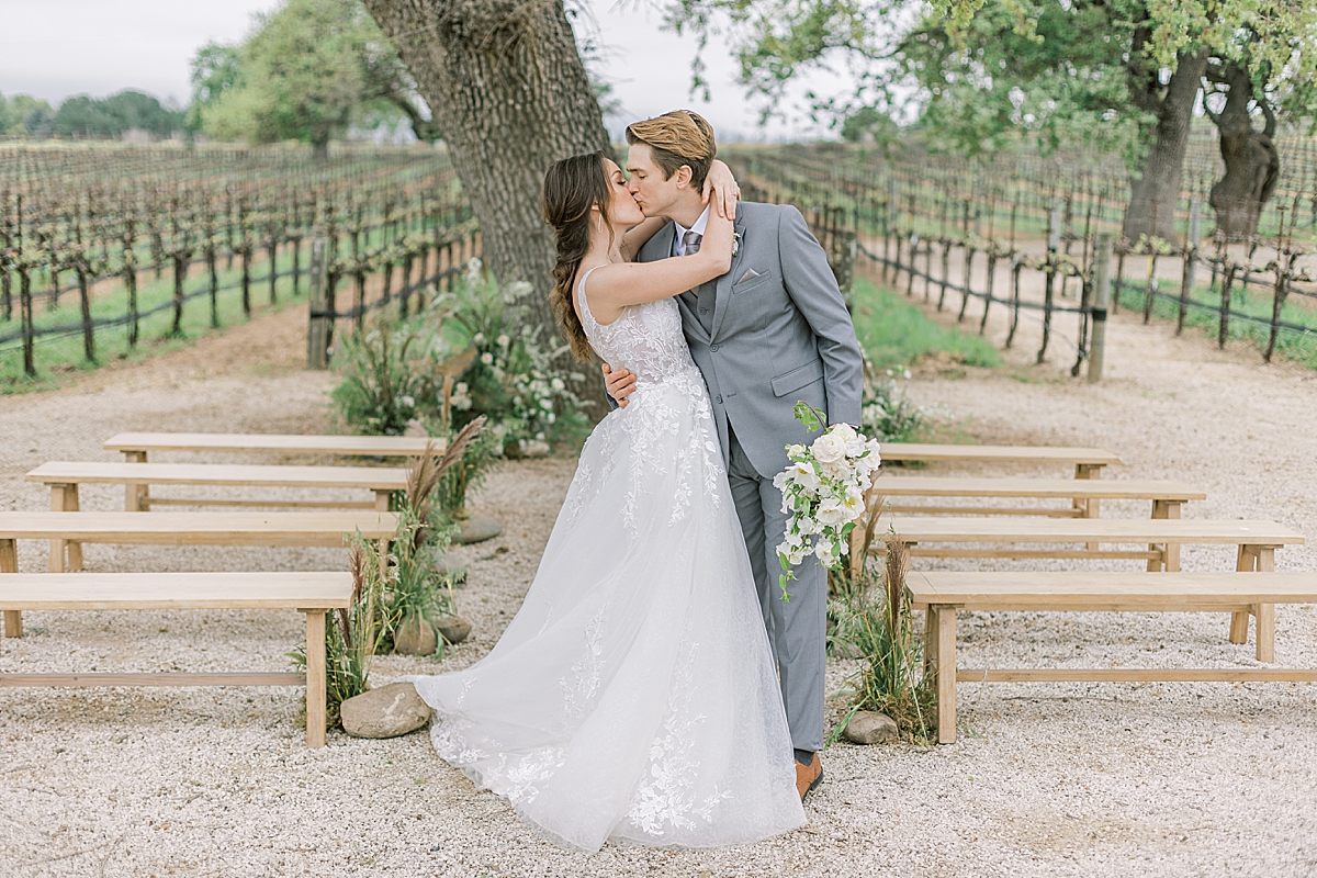 The couple sharing a kiss at the end of the ceremony aisle at their Southern California Winery Wedding