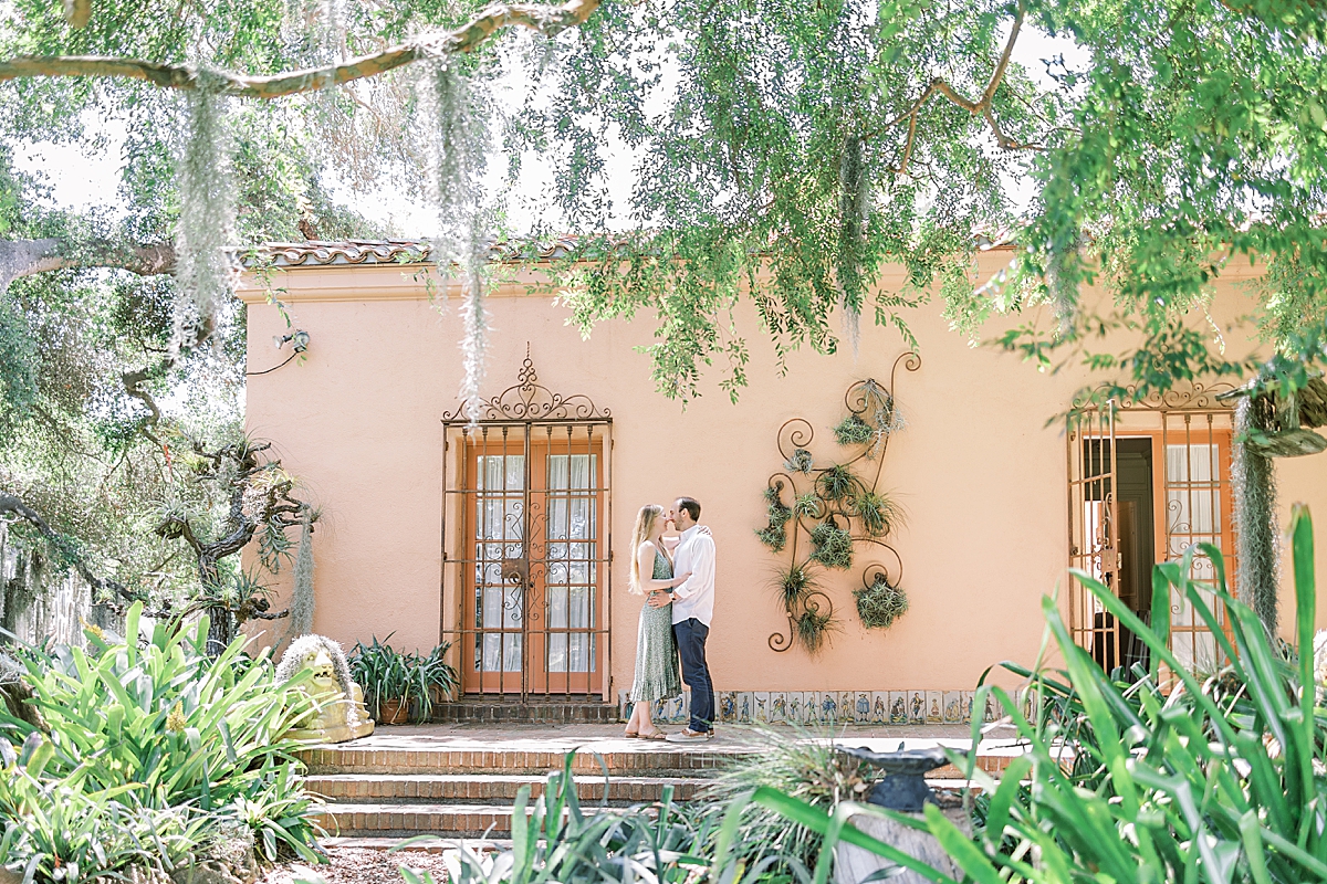 The couple sharing a kiss on the back patio of a building at Lotusland in Montecito, California after he proposed.
