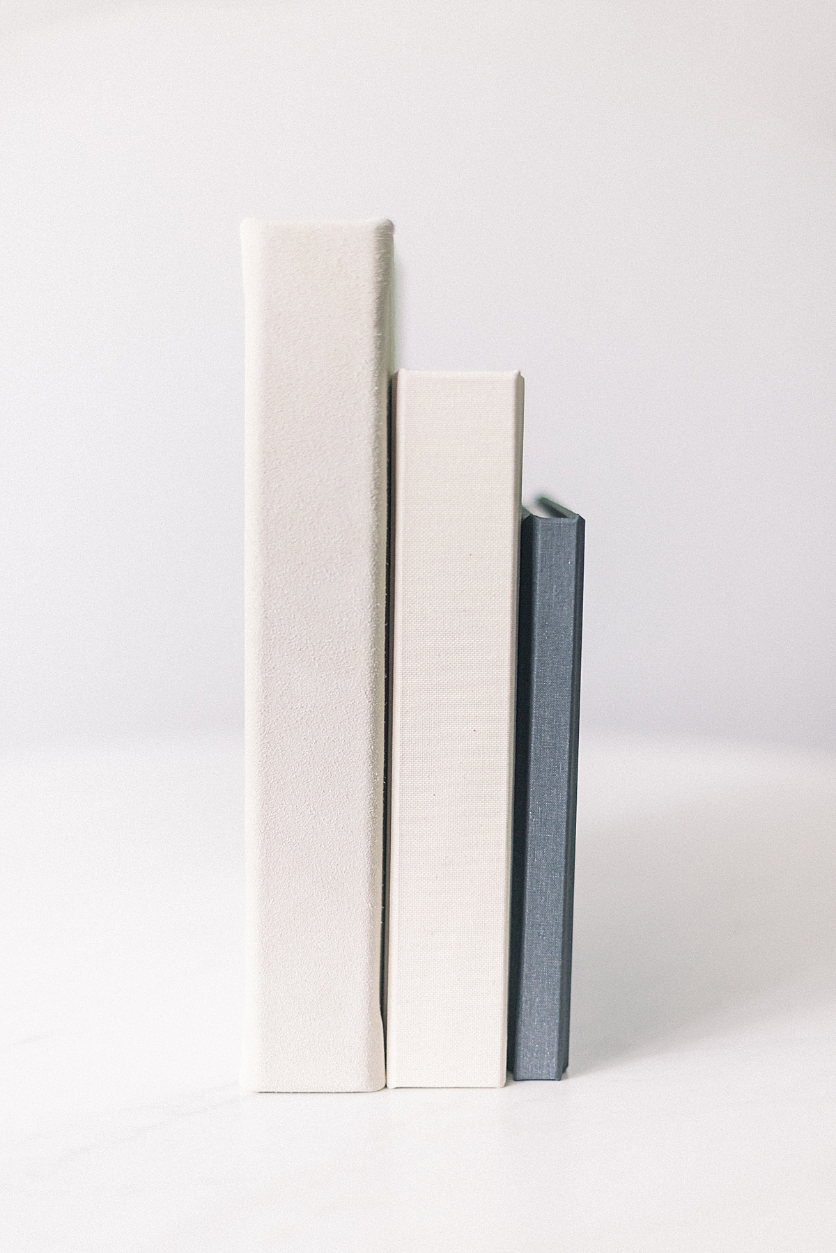 Three wedding albums standing upright to show size and material differences.