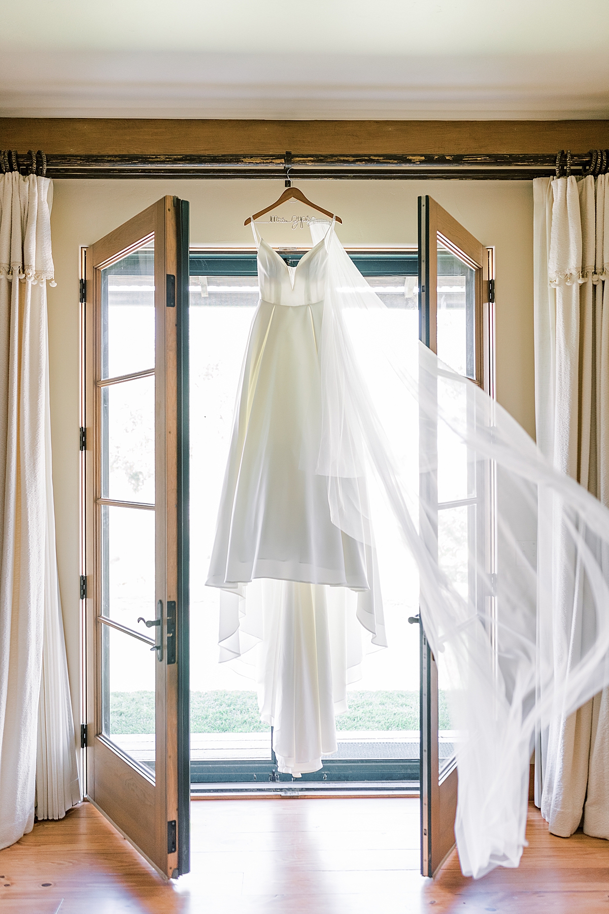 Kat's wedding dress hanging from a bar and blowing in the wind at their San Luis Obispo Mission wedding venue.
