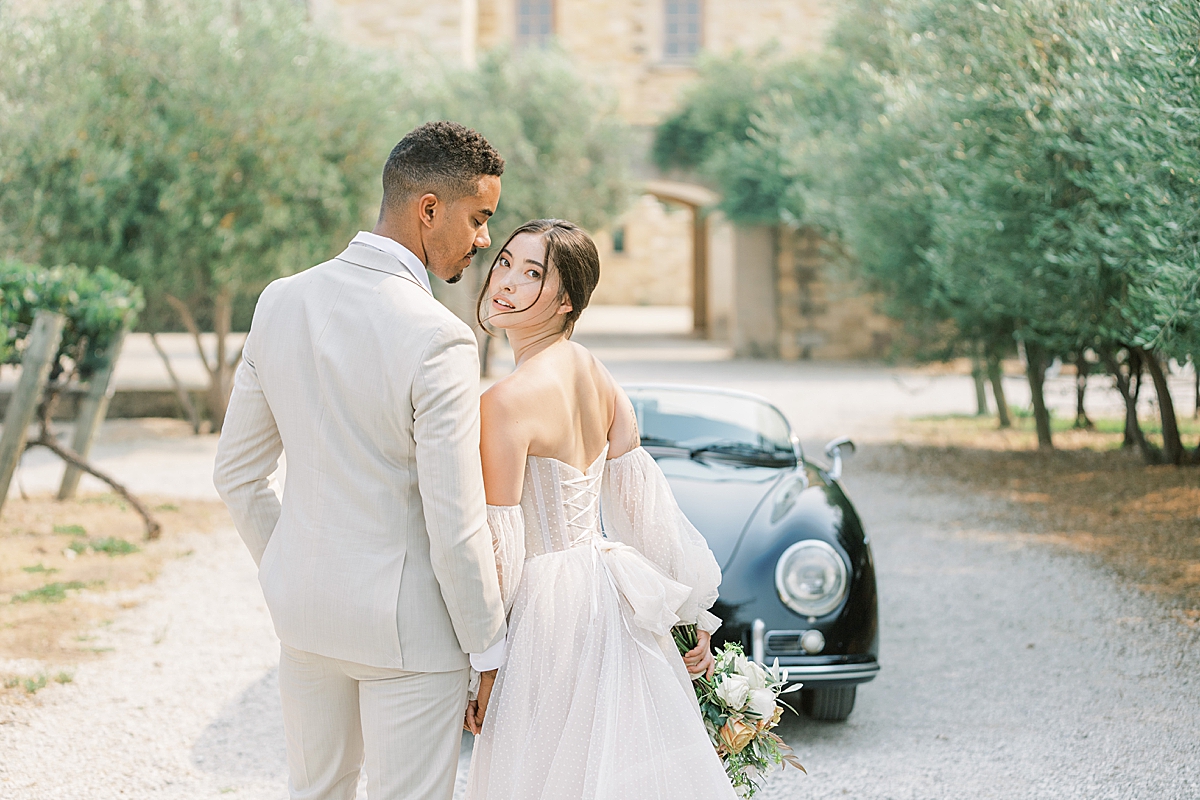 A bride staring over her should while holding her groom's hand. She's wearing a wedding gown that she purchased from one of our favorite Bridal Boutiques in Los Angeles