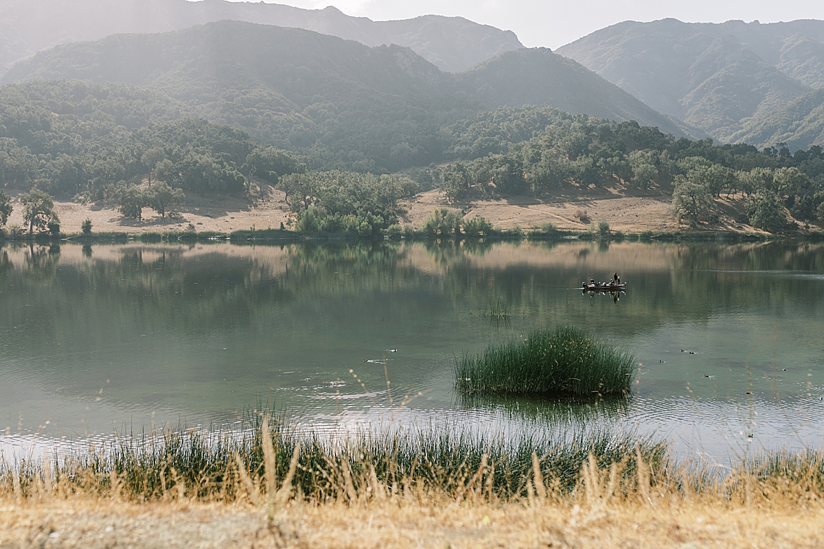 The private lake at Alisal Ranch and mountains covered in trees in the distance.